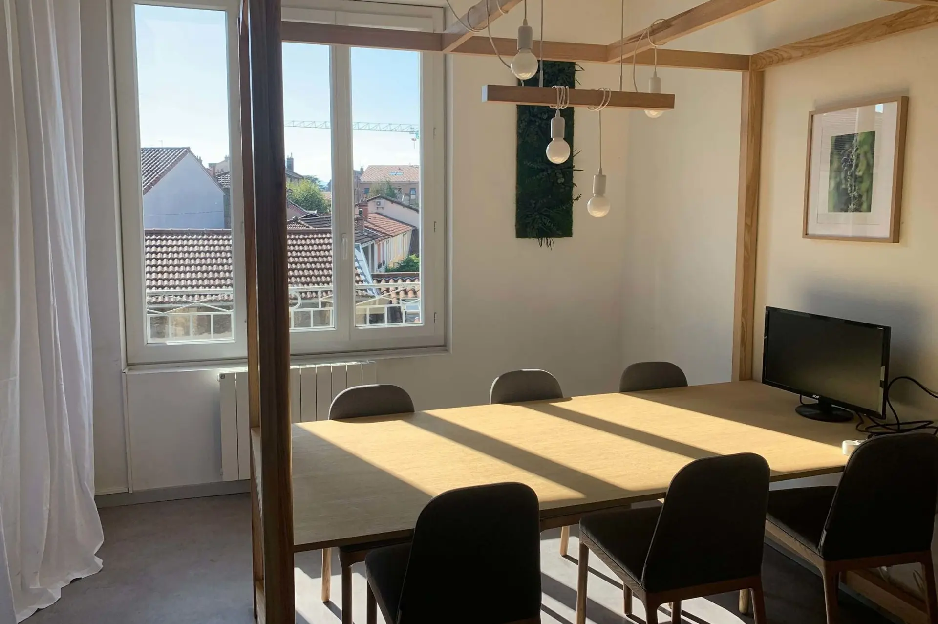 MIX d'à côté, grande pièces au troisième étage, grande table au milieu avec des chaises. Luminaire au dessus, pièce spacieuse avec un écran.