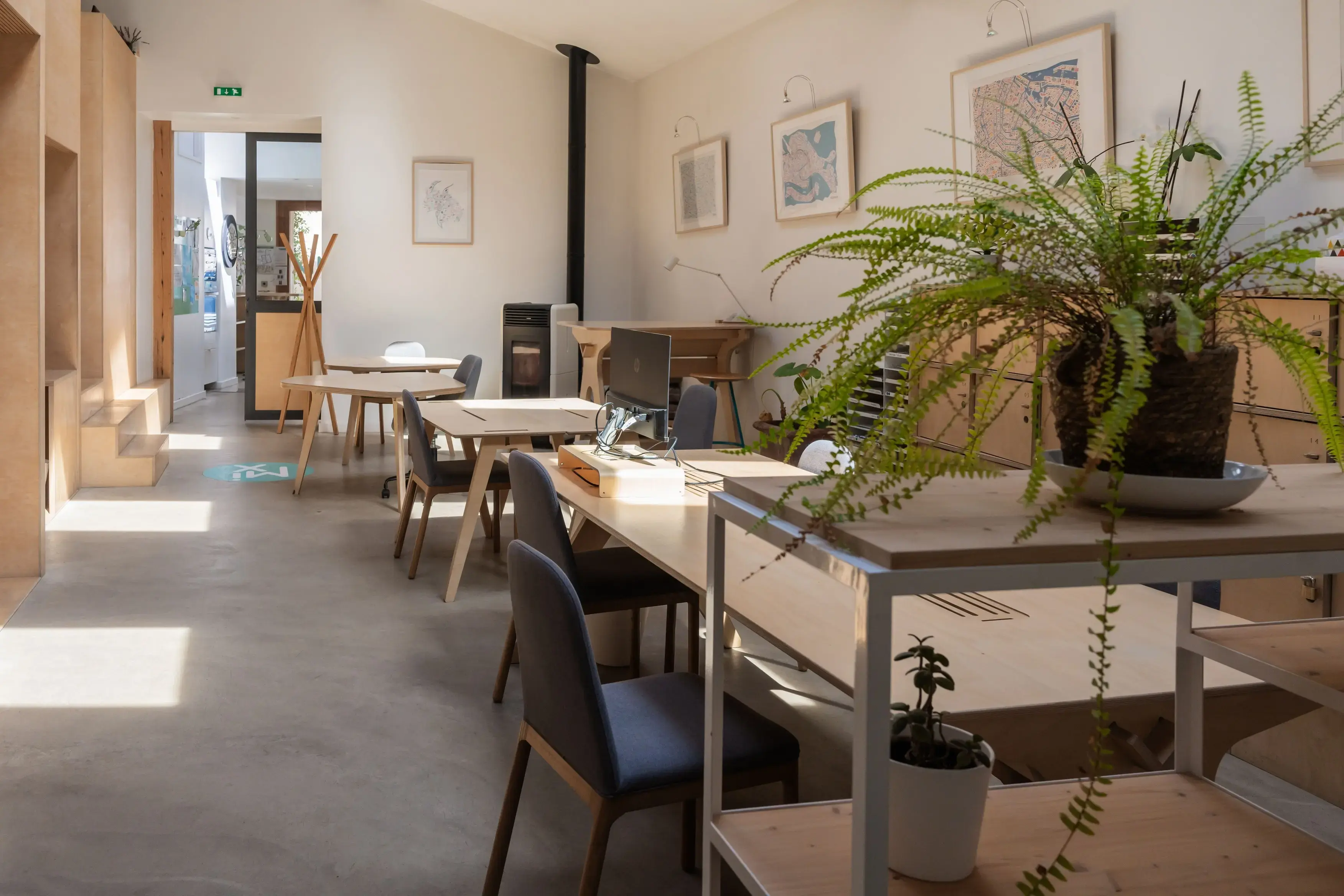 Espace de travail ouvert du MIX Coworking, larges tables en longueur avec chaises confortables et poêle