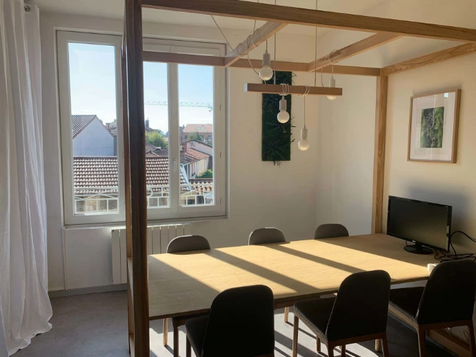 MIX d'à côté, grande pièces au troisième étage, grande table au milieu avec des chaises. Luminaire au dessus, pièce spacieuse avec un écran.