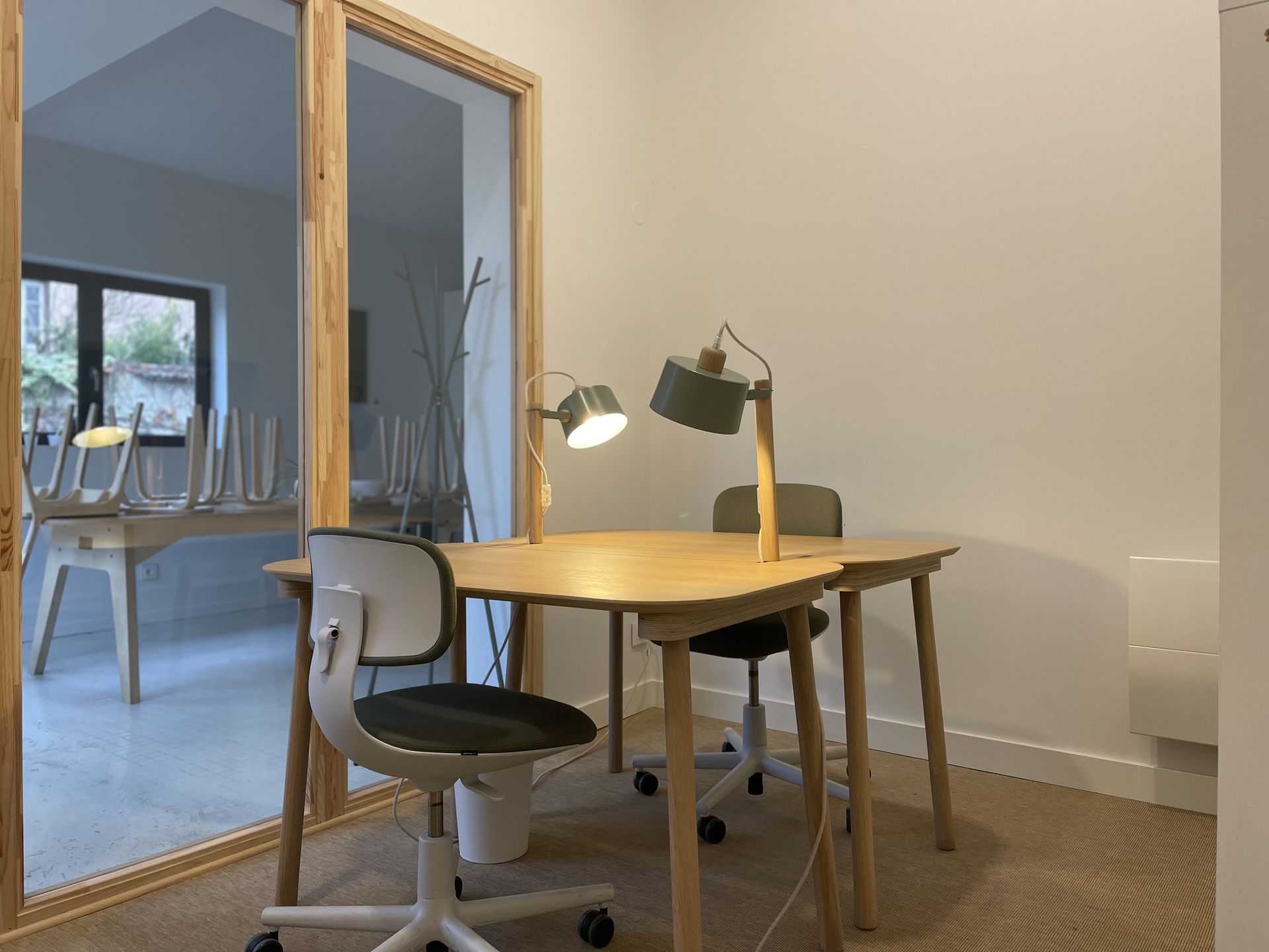Bureau privé au MIX Café, grande pièce avec deux tables, deux chaises roulantes, deux lampes et des casiers, moquette au sol